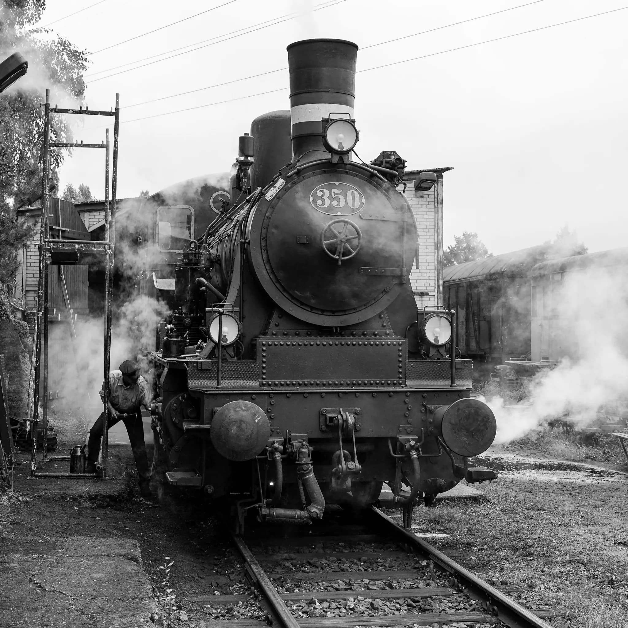 A worker at the front of a steam locomotive under steam