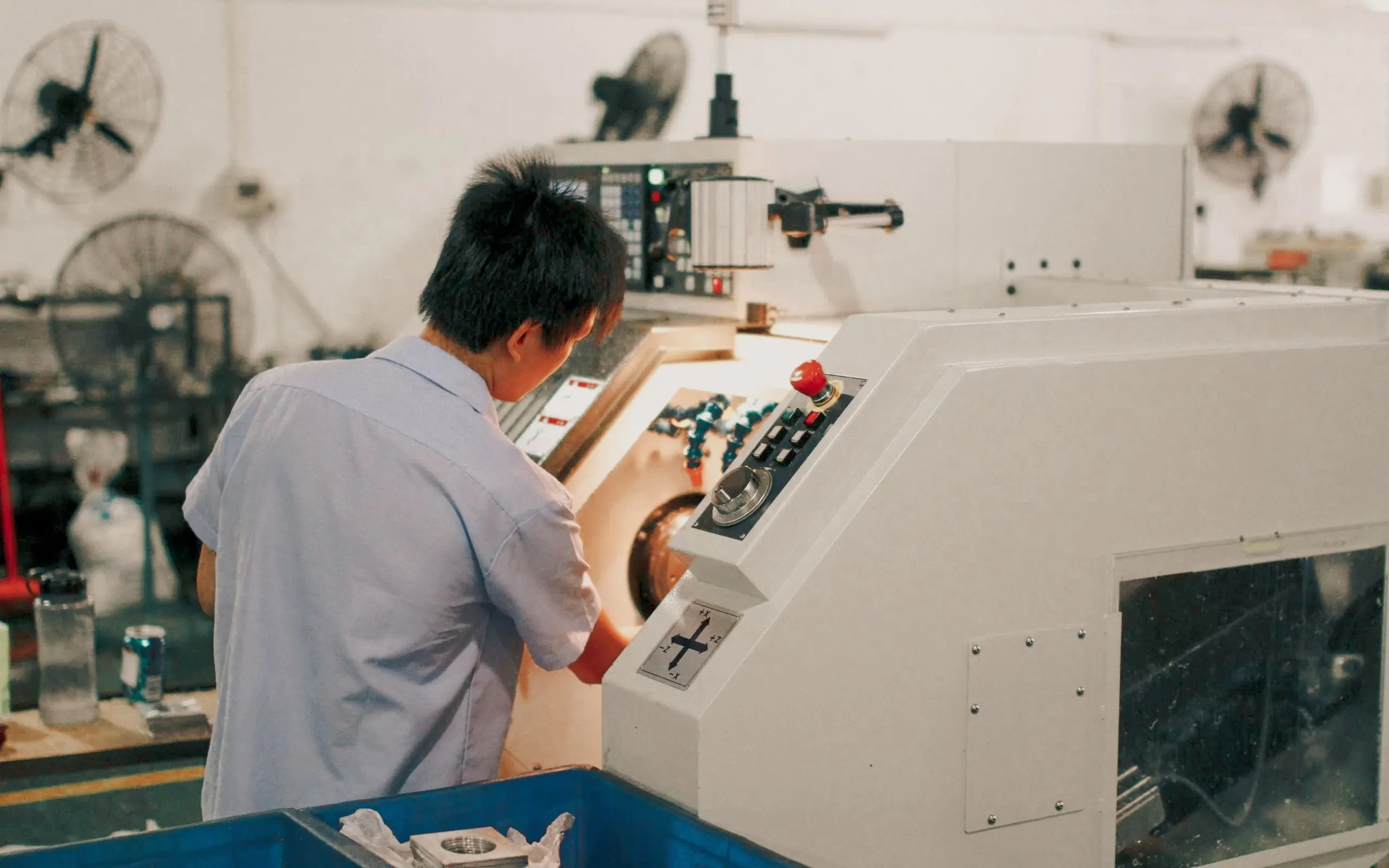 An operator at the control panel of a CNC lathe